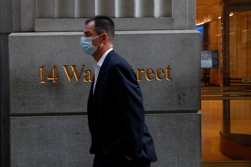 &copy; Reuters. FILE PHOTO: A man wearing a protective face mask walks by 14 Wall Street, as the global outbreak of the coronavirus disease (COVID-19) continues, in the financial district of New York