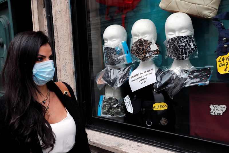 &copy; Reuters. Una mujer pasa por delante de una tienda donde se exhiben mascarillas protectoras, después de que el gobierno anunció medidas más duras para combatir la propagación de la enfermedad coronavirus (COVID-19), en Roma, Italia.