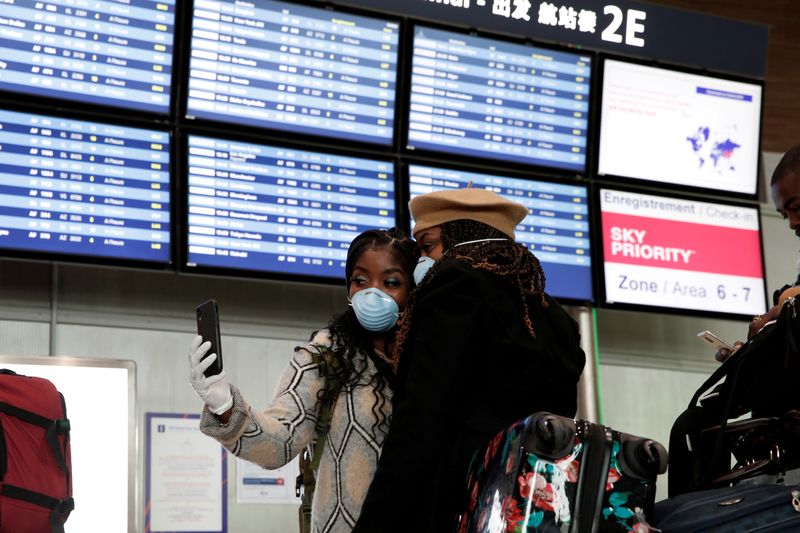 &copy; Reuters. Dei passeggeri con indosso la mascherina si fanno un selfie all&apos;aeroporto Charles de Gaulle a Roissy,