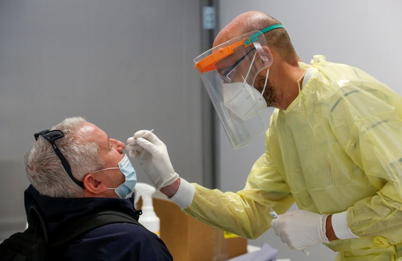 &copy; Reuters. FILE PHOTO: A health worker takes a swab sample from a man to test for the coronavirus disease (COVID-19), at the Fiumicino Airport in Rome