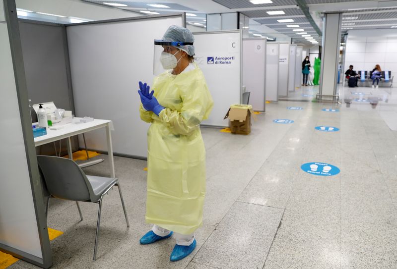 &copy; Reuters. Un operatore sanitario indossa un dispositivo di protezione individuale (Dpi) per condurre i test per la malattia da coronavirus (Covid-19), all&apos;aeroporto di Fiumicino a Roma