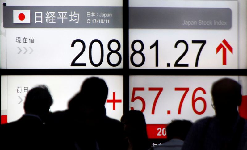 &copy; Reuters. People walk past an electronic board showing Japan&apos;s Nikkei average outside a brokerage in Tokyo