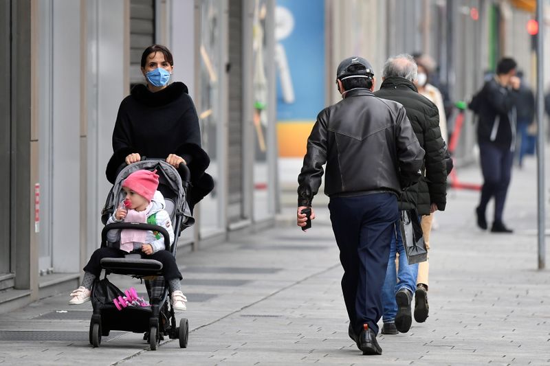 &copy; Reuters. Delle persone con indosso la mascherina passeggiano a Milano
