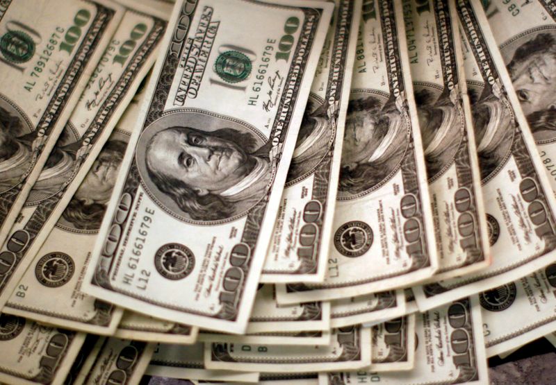 © Reuters. FILE PHOTO: U.S. dollars are counted out by a banker at a bank in Westminster