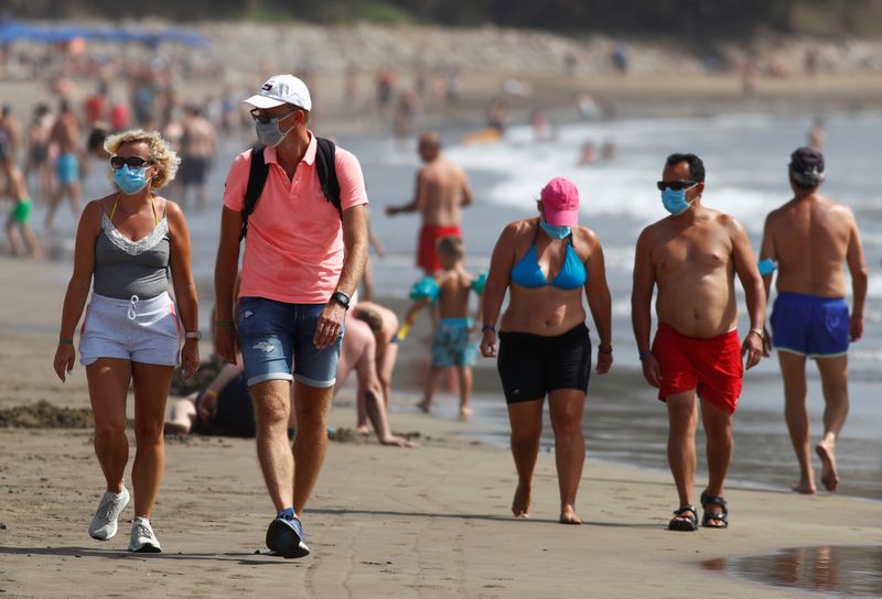 &copy; Reuters. FILE PHOTO: Several people walk along the beach wearing face masks, as the regional government of the Canary Islands forbids smoking without maintaining a safe distance