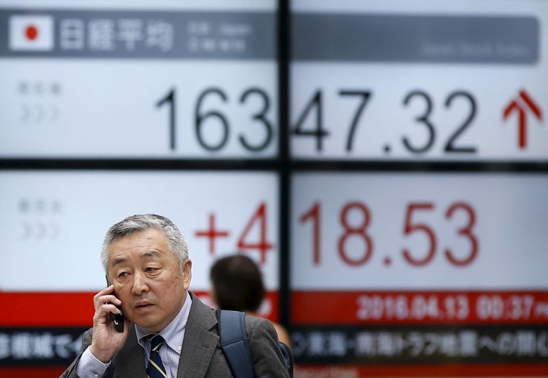 &copy; Reuters. A man walks in front of an electronic board showing Japan&apos;s Nikkei average outside a brokerage in Tokyo