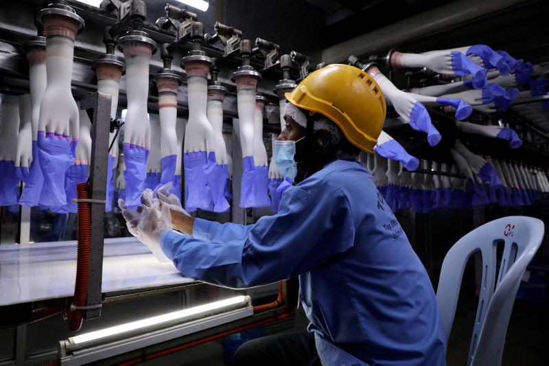 &copy; Reuters. FILE PHOTO: A worker inspects newly-made gloves at Top Glove factory in Shah Alam