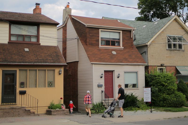 &copy; Reuters. FILE PHOTO: A family passes a house for sale listed at a price of $999,000 ($799,000 USD) on Mount Pleasant Road in Toronto