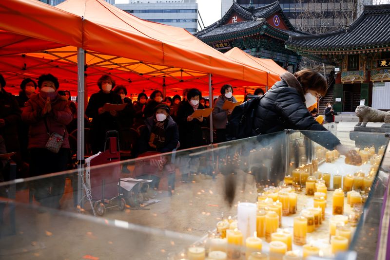 © Reuters. A mother lights a candle as she prays for children’s success in the college entrance examinations amid the coronavirus disease (COVID-19) pandemic, at a Buddhist temple in Seoul