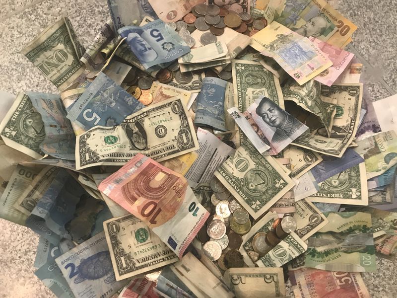 © Reuters. FILE PHOTO: U.S. dollars and other world currencies lie in a charity receptacle at Pearson international airport in Toronto