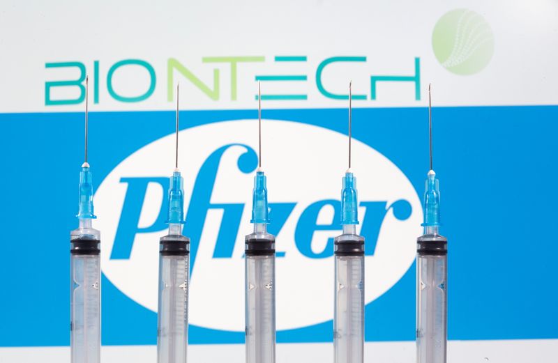 &copy; Reuters. Cinque siringhe davanti ai logo Pfizer e BioNTech