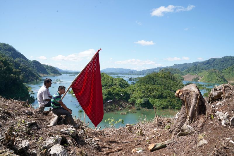 &copy; Reuters. People hold a flag while sitting on the top of a mountain, in the hope of attracting military helicopters delivering aid to villages affected by Hurricanes Eta and Iota, in Alta Verapaz