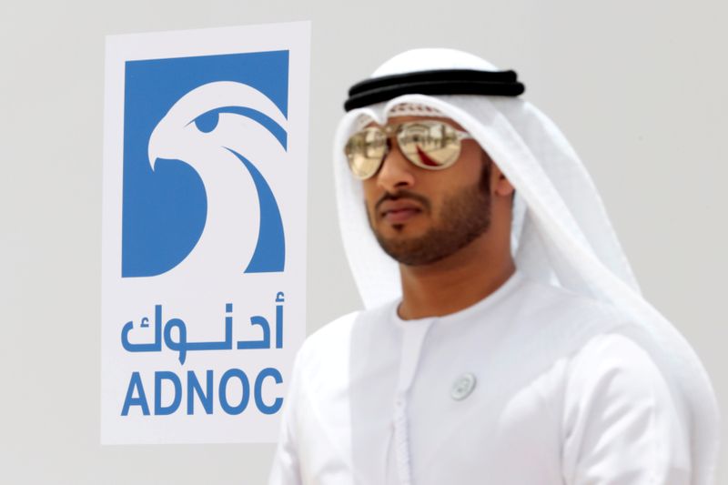© Reuters. FILE PHOTO: An Emirati man is seen near the logo of  ADNOC in Ruwais