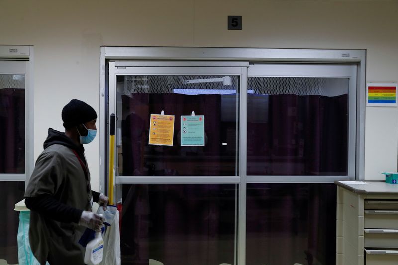 © Reuters. FILE PHOTO:  A housekeeper walks by the isolation room of a coronavirus disease (COVID-19) positive patient inside the emergency room bed at Roseland Community Hospital on the South Side of Chicago, Illinois