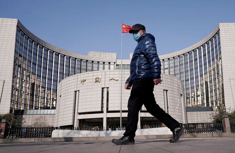 &copy; Reuters. Man wearing a mask walks past the headquarters of the People&apos;s Bank of China, the central bank, in Beijing