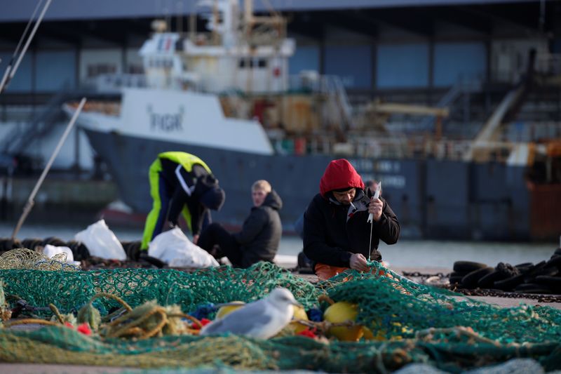 © Reuters. Imagen de archivo de pescadores reparando una red de pesca en el puerto de Boulogne-sur-Mer