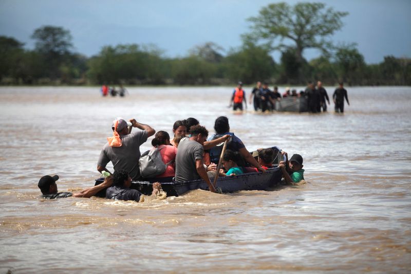 &copy; Reuters. FILE PHOTO: Flood-affected people get on a boat to cross a street after passage of Storm Eta, in La Lima