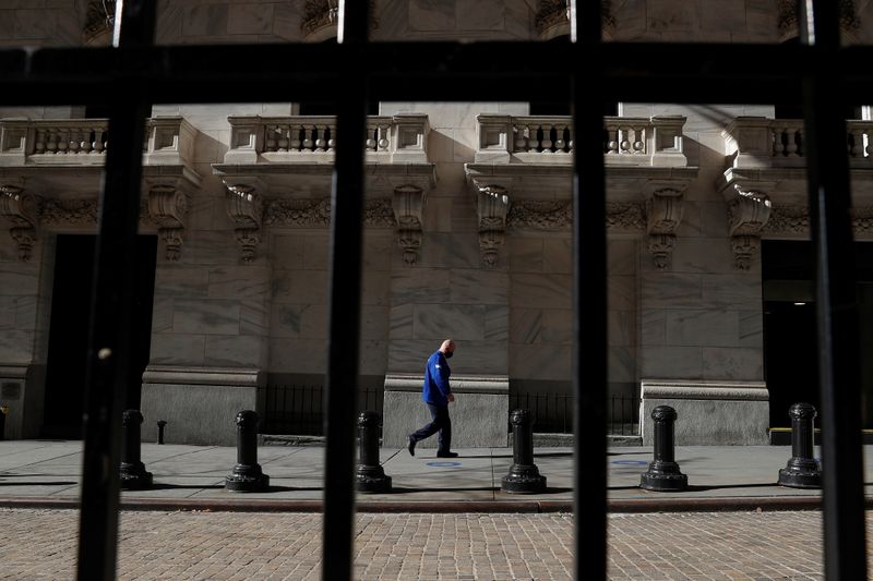 © Reuters. FILE PHOTO: A trader wearing a protective face mask walks, as the global outbreak of the coronavirus disease (COVID-19) continues, at the New York Stock Exchange (NYSE) in the financial district of New York