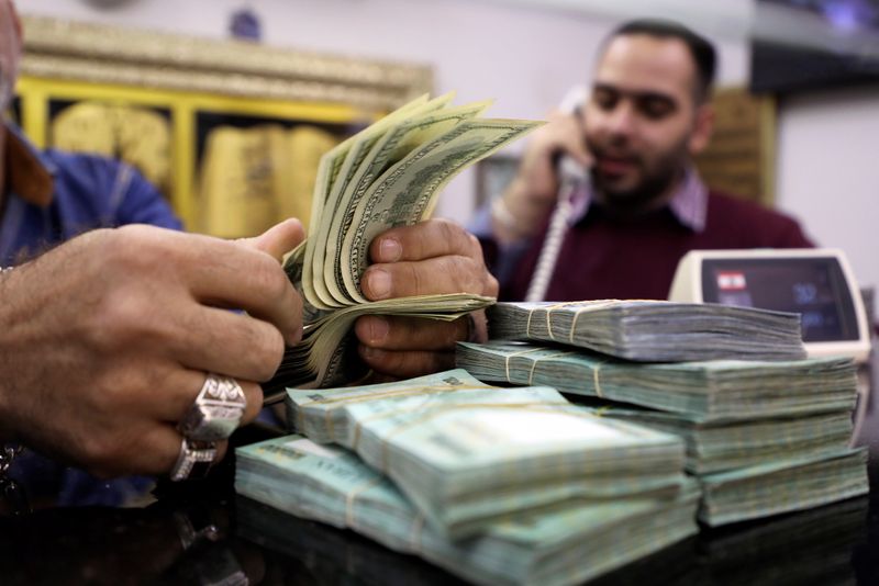 &copy; Reuters. A man counts U.S. dollar banknotes next to Lebanese pounds at a currency exchange shop in Beirut