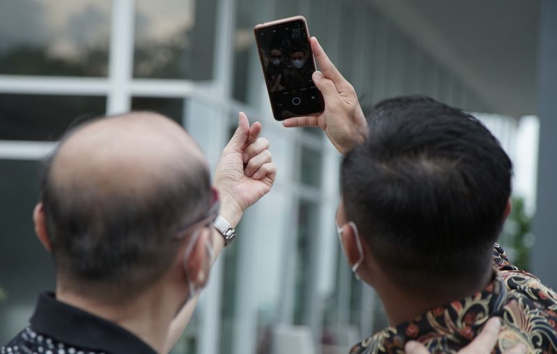 &copy; Reuters. Tri Teguh Pujianto, a 31-year-old former police brigadier who was fired in 2018 after 10 years on the job, holds a phone while taking selfie with his partner at a restaurant in Semarang