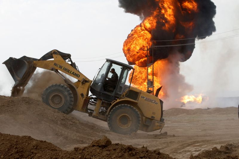 © Reuters. A machinery is seen as oil wells burn inside the Khabbaz oilfield after they were bombed on the outskirts of Kirkuk