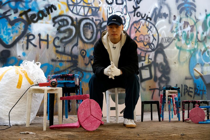 &copy; Reuters. Kim Ha-neul, who is majoring in furniture design, poses for photographs with his upcycled stools made from discarded protective masks in Uiwang, South Korea