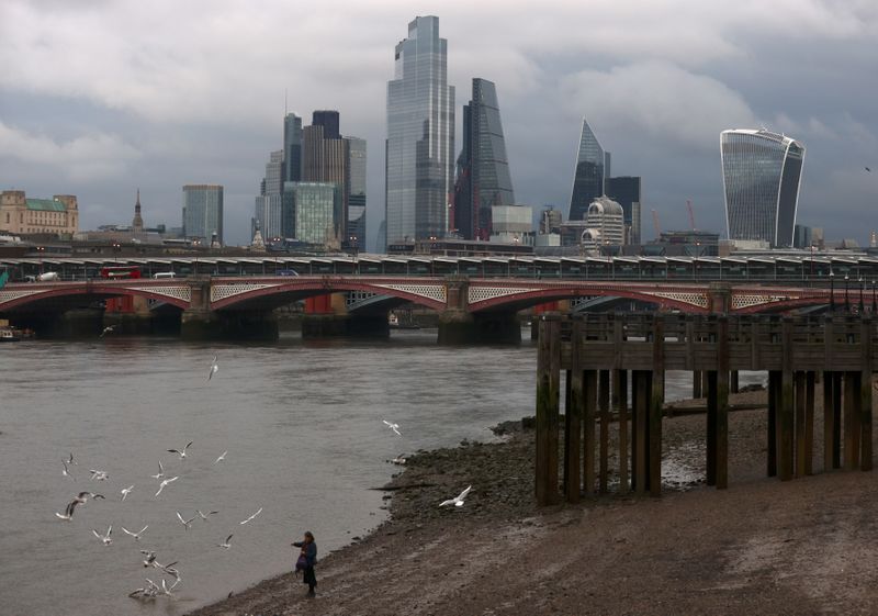 &copy; Reuters. A woman feeds birds on the bank of the river Thames with London&apos;s financial district seen in the background, amid the coronavirus disease (COVID-19) in London