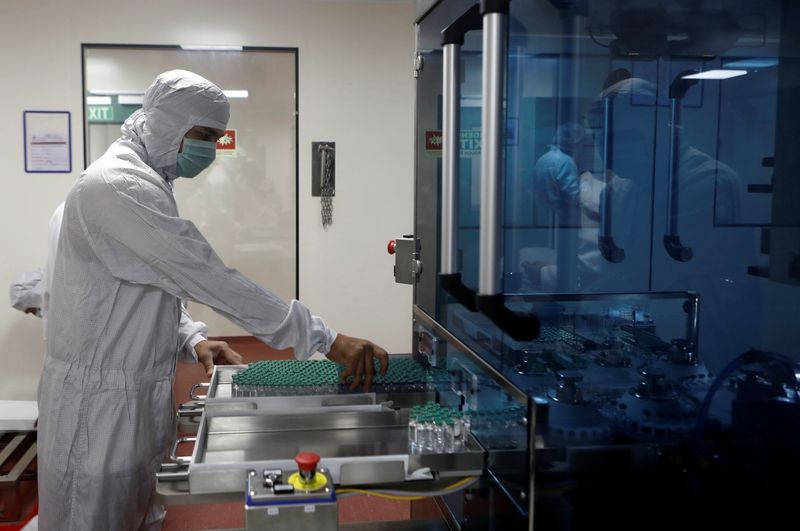 © Reuters. An employee in personal protective equipment (PPE) removes vials of AstraZeneca's COVISHIELD, coronavirus disease (COVID-19) vaccine from a visual inspection machine inside a lab at Serum Institute of India, in Pune