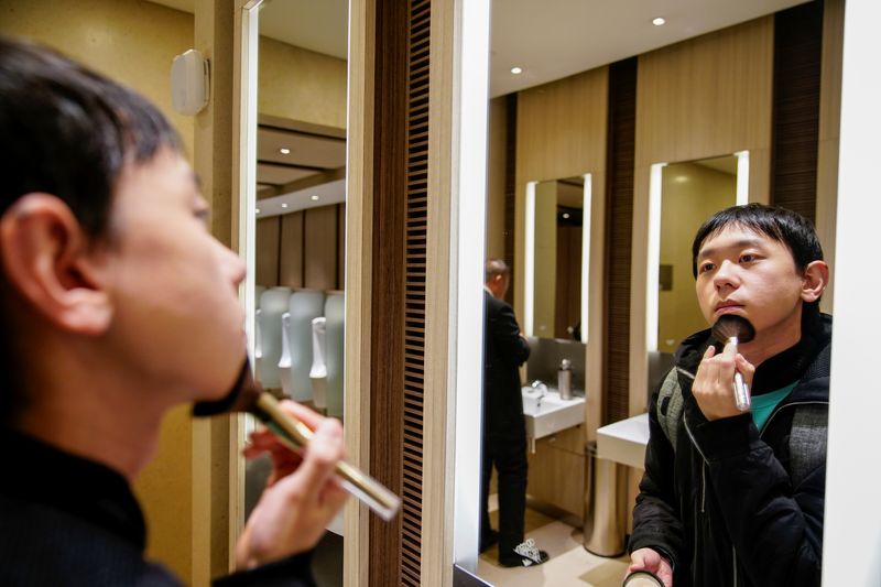 © Reuters. Liu Yuxuan, 22, a student, puts on his make-up at a restroom in a shopping mall in Shanghai