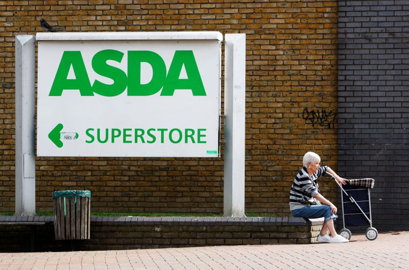 © Reuters. FILE PHOTO: A shopper sits by an Asda superstore sign in south London