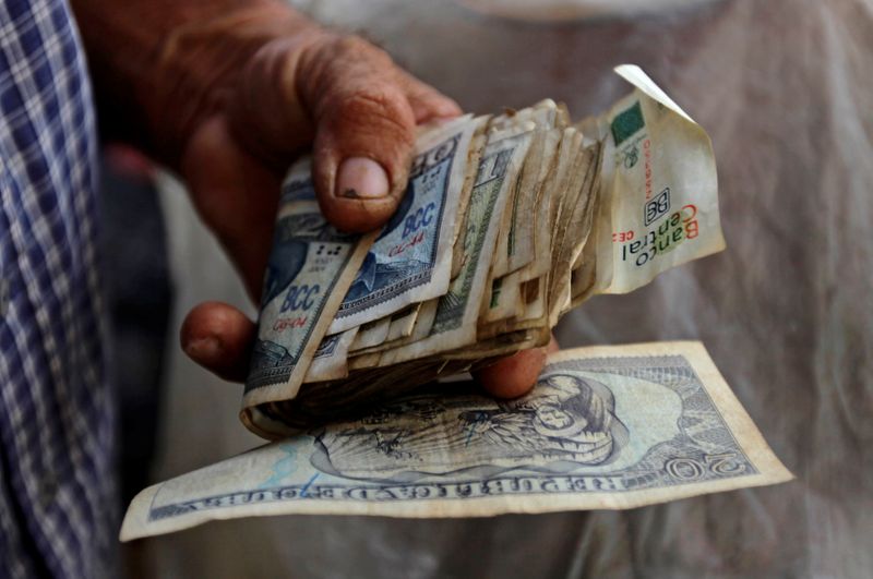 © Reuters.  FOTO DE ARCHIVO: Un agricultor sostiene un fajo de dinero cubano en un puesto de verduras en un mercado en el centro de Cuba.
