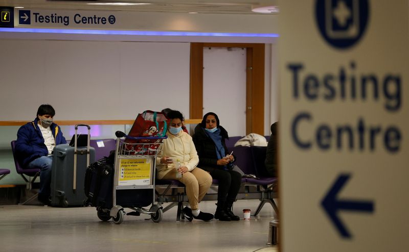 &copy; Reuters. FILE PHOTO: Passengers sit beneath a testing centre sign in the terminal building of Manchester Airport amid the outbreak of the coronavirus disease (COVID-19) in Manchester