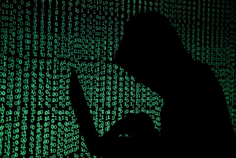 &copy; Reuters. Hooded man holds laptop computer as cyber code is projected on him in this illustration picture