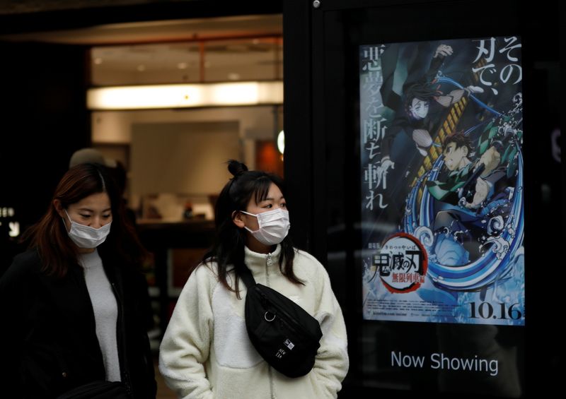&copy; Reuters. Women wearing protective masks amid the coronavirus disease (COVID-19) outbreak walk past a poster for an animated movie &quot;Demon slayer&quot; in front of a movie theatre in Tokyo