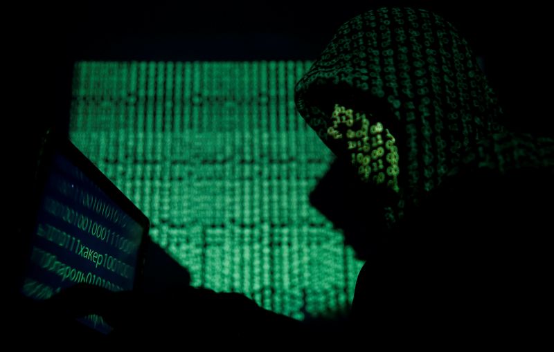 &copy; Reuters. FILE PHOTO: Hooded man holds a laptop computer as cyber code is projected on him in this illustration picture