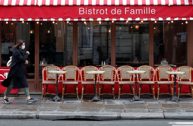 &copy; Reuters. FILE PHOTO: A woman wearing a protective face mask walks past a restaurant in Paris