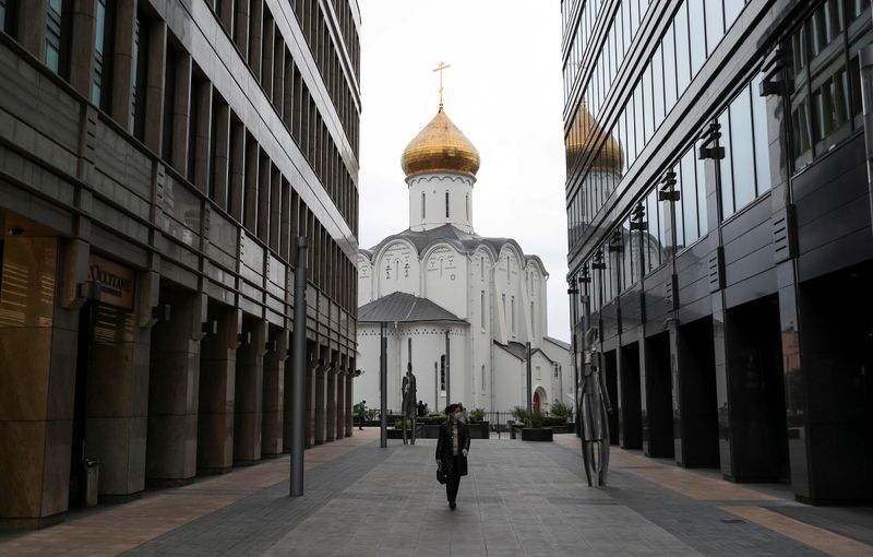 &copy; Reuters. FILE PHOTO: A woman wearing a protective face mask walks walks in a business district in Moscow