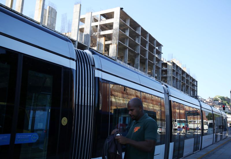 &copy; Reuters. A man waits at a tram station in front of an abandoned unfinished building in Rio de Janeiro