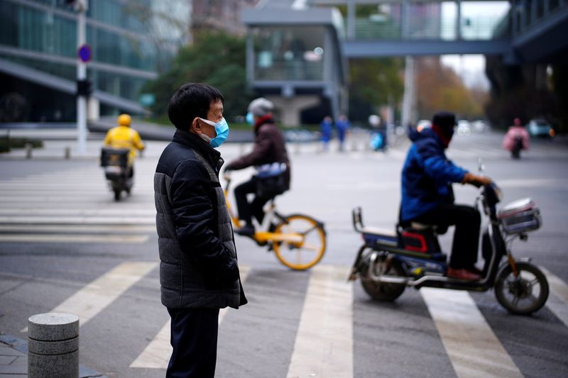 &copy; Reuters. Man wearing a mask stands near a street, almost a year after the start of the coronavirus disease (COVID-19) outbreak, in Wuhan, Hubei