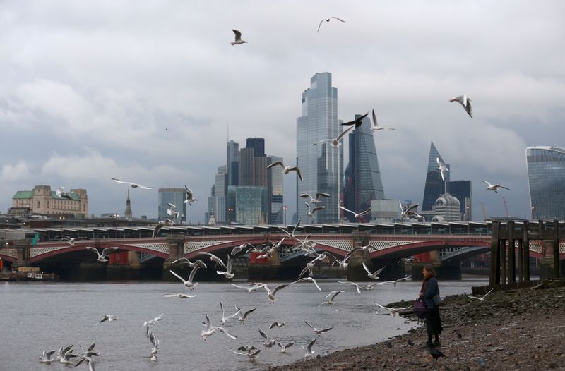 © Reuters. FILE PHOTO: A woman feeds birds on the bank of the river Thames with London's financial district seen in the background, amid the coronavirus disease (COVID-19) in London