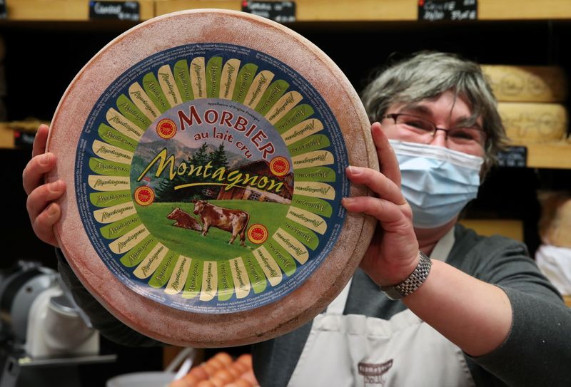 &copy; Reuters. The owner of a shop specialised in cheeses shows a wheel of Morbier cheese, in Brussels