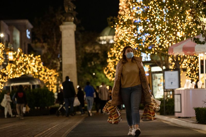 &copy; Reuters. A shopper wearing a face protective mask walks by Christmas decorations at The Grove shopping center during a partial lockdown amid the outbreak of the coronavirus disease (COVID-19), in Los Angeles