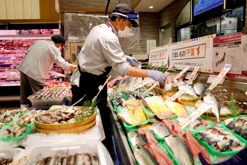 &copy; Reuters. FILE PHOTO: A staff wearing a face shield sells fish at Japan&apos;s supermarket group Aeon&apos;s shopping mall as the mall reopens amid the coronavirus disease (COVID-19) outbreak in Chiba