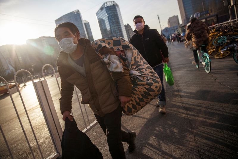 &copy; Reuters. People wear face masks as they walk outside a bus terminal following an outbreak of the coronavirus disease (COVID-19) in Beijing