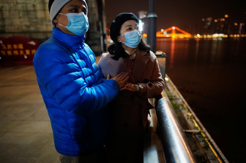 &copy; Reuters. Duan Ling’s husband Fang Yushun warms her hand during a cold winter’s night as they take a walk outside, almost a year after the global outbreak of the coronavirus disease (COVID-19) in Wuhan