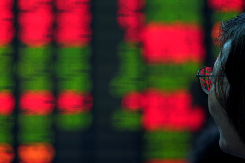 &copy; Reuters. Un investitori osserva un tabellone elettronico nei pressi del distretto finanziario di Shanghai