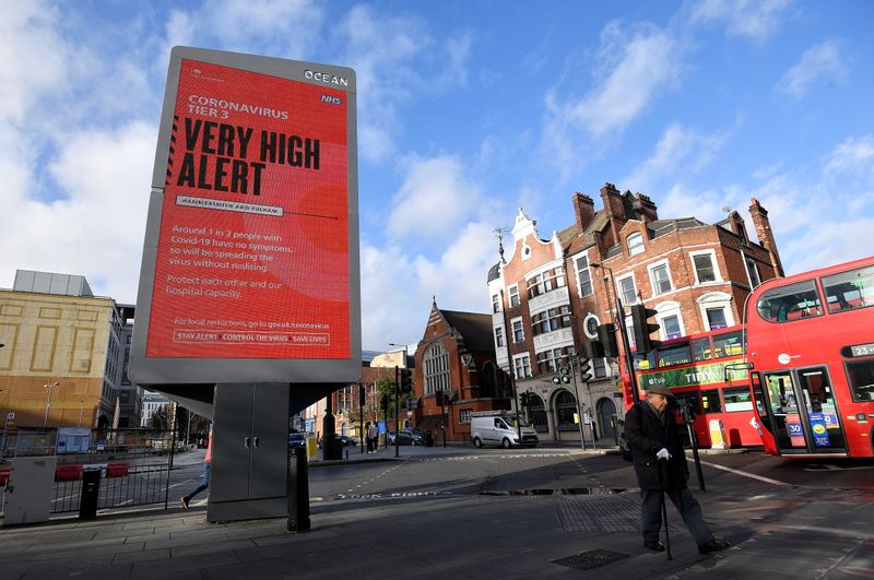 &copy; Reuters. Pedestrians walk past a British government health information advertisement highlighting new restrictions amid the spread of the coronavirus disease (COVID-19), London, Britain