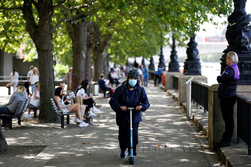 &copy; Reuters. FILE PHOTO: A woman wearing a protective face mask rides a scooter along the South Bank, amid the spread of coronavirus disease (COVID-19), in London