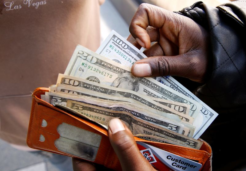 © Reuters.  Một người đàn ông trưng bày các tờ tiền đô la Mỹ sau khi rút tiền mặt từ ngân hàng ở Harare