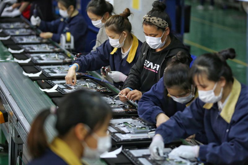 &copy; Reuters. FILE PHOTO: Employees wearing masks work on a production line manufacturing display monitors at a TPV factory in Wuhan